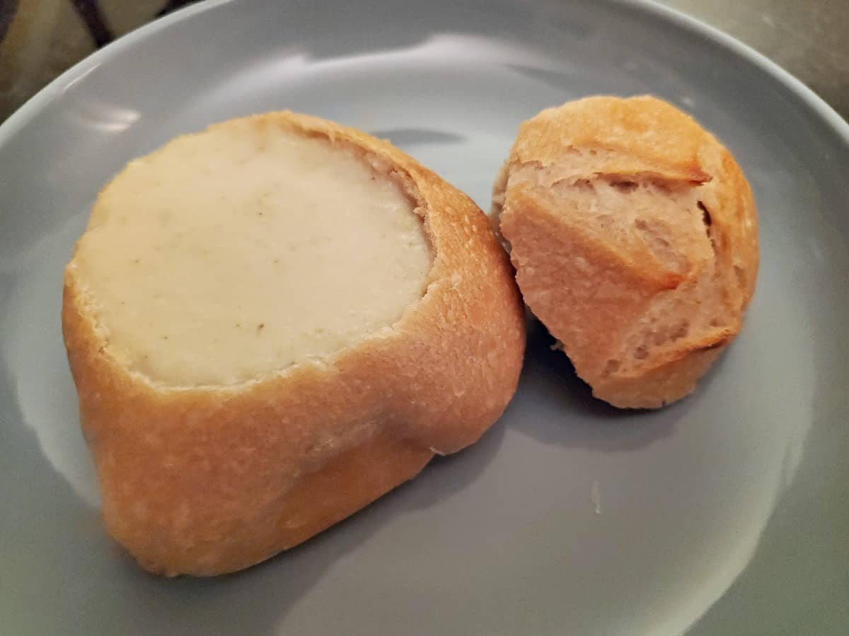 Cream of celery soup in a sourdough bread bowl on a blue soup.