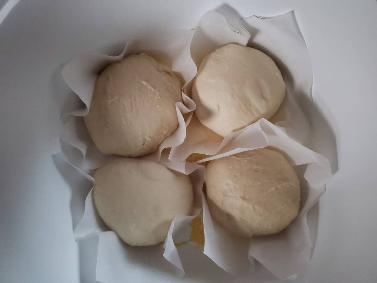 Four sourdough bread bowls on parchment paper in a white pot,