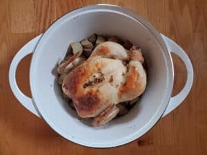 Perfect lemon roast chicken in a white dutch oven.