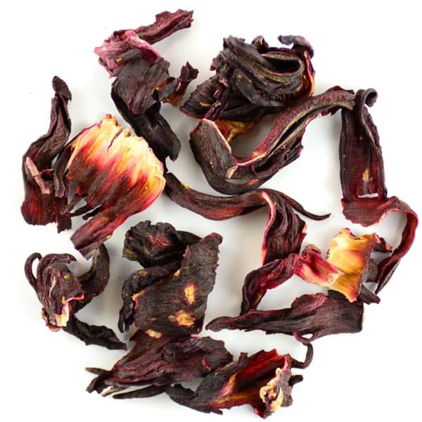 Close up of loose leaf hibiscus tea on a white background.