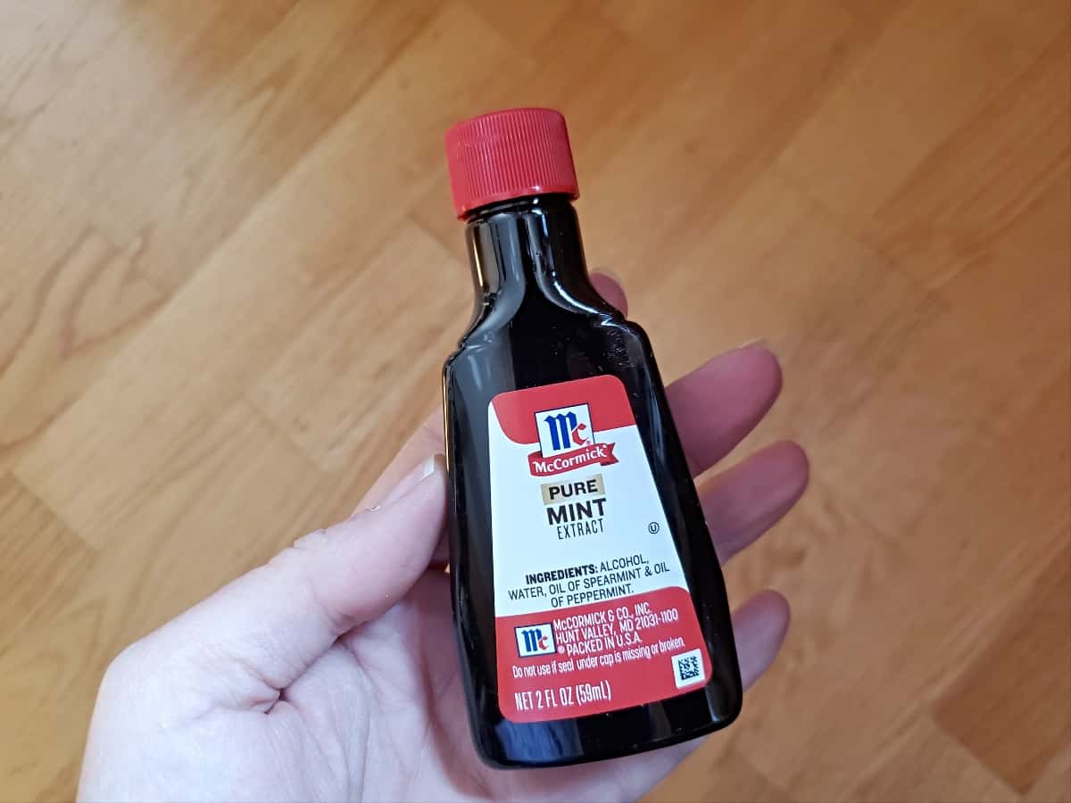Hand holding a bottle of pure mint extract.