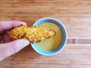 Dipping a chicken tender into honey mustard sauce.