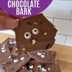 Image shows a Hand holding Halloween bark with text no bake Halloween treat simple chocolate bark.