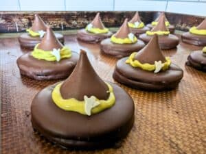 Image shows Witch hat oreos on a silpat in a baking tray.