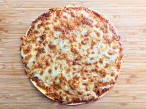 Image shows cooked tortilla pizza on a wooden tray.
