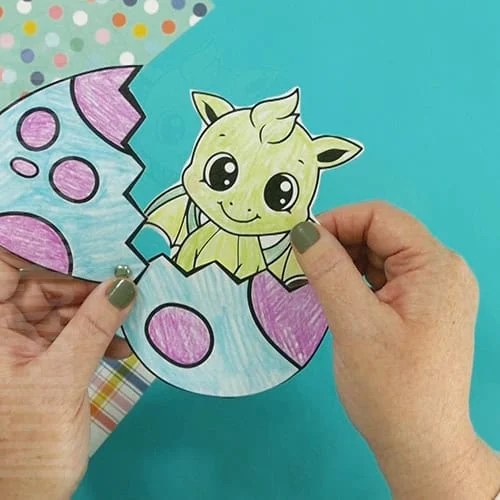 An image showing a baby dragon craft printable, perfect for a fairy tale craft where kids can color and assemble their own baby dragon in an egg.