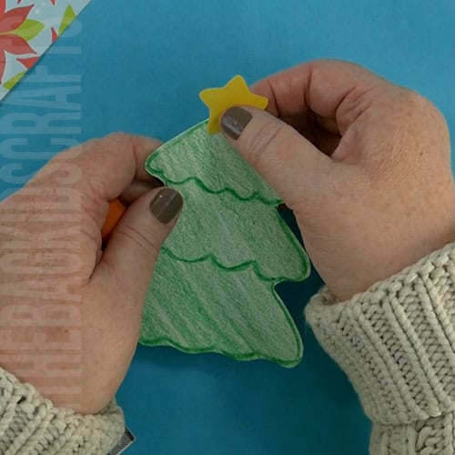 A completed Christmas tree craft made with green paper, colorful beads, pipe cleaners, and a star topper, perfect as an easy craft for kids and a festive Christmas tree craft.  step 3 gluing on the christmas star 