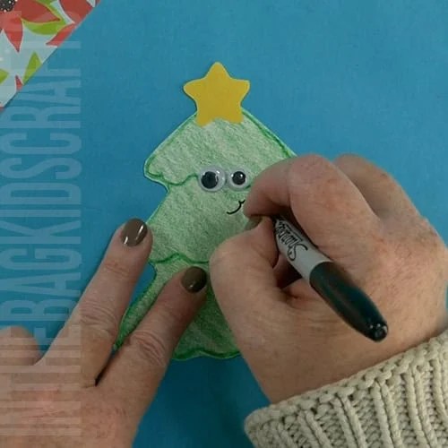 A completed Christmas tree craft made with green paper, colorful beads, pipe cleaners, and a star topper, perfect as an easy craft for kids and a festive Christmas tree craft.  step 5 adding the face 