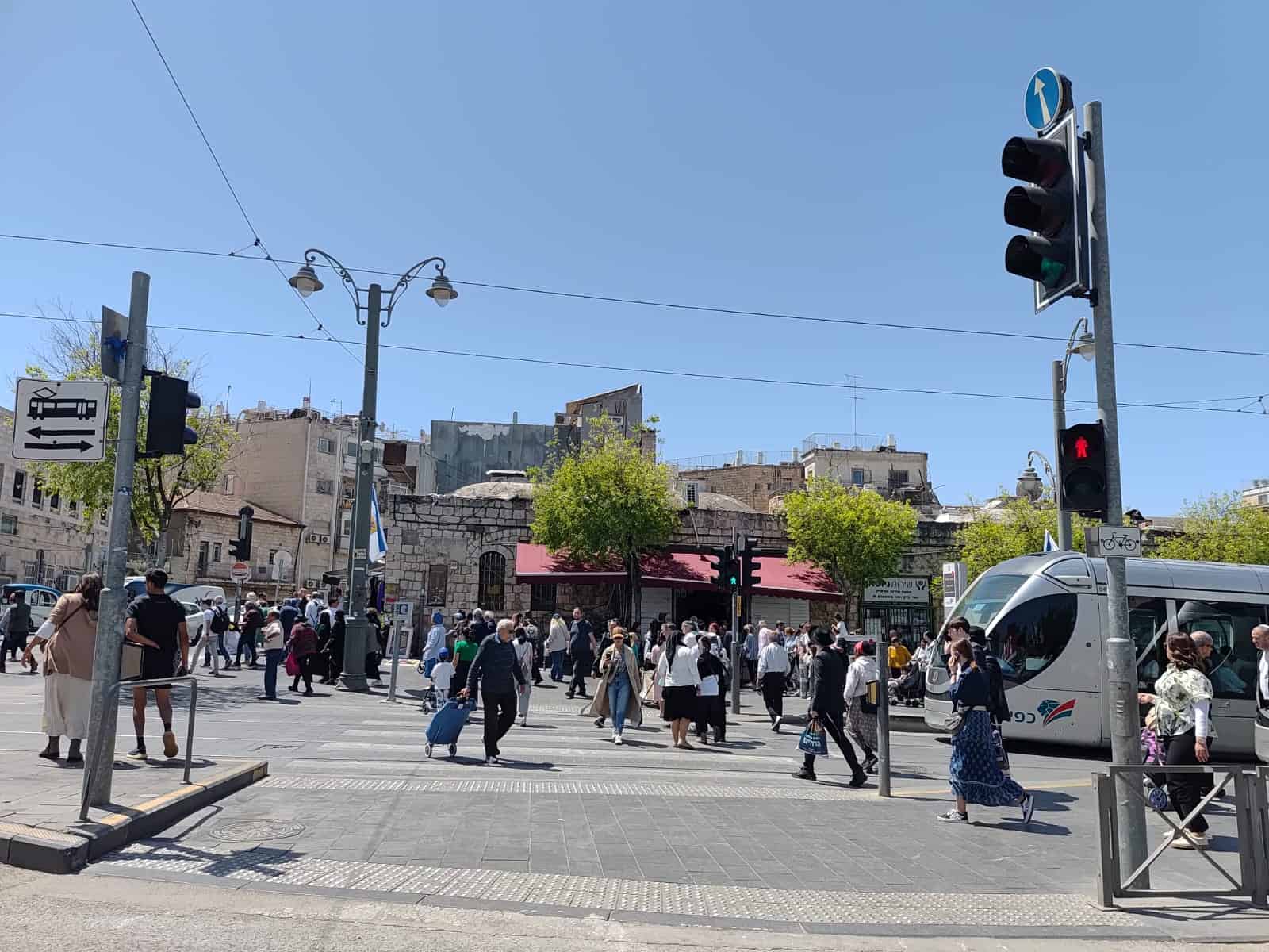 עוברים ושבים חוצים את הכביש ליד תחנת כיכר ציון בירושלים, יום אחרי חג העצמאות 2025