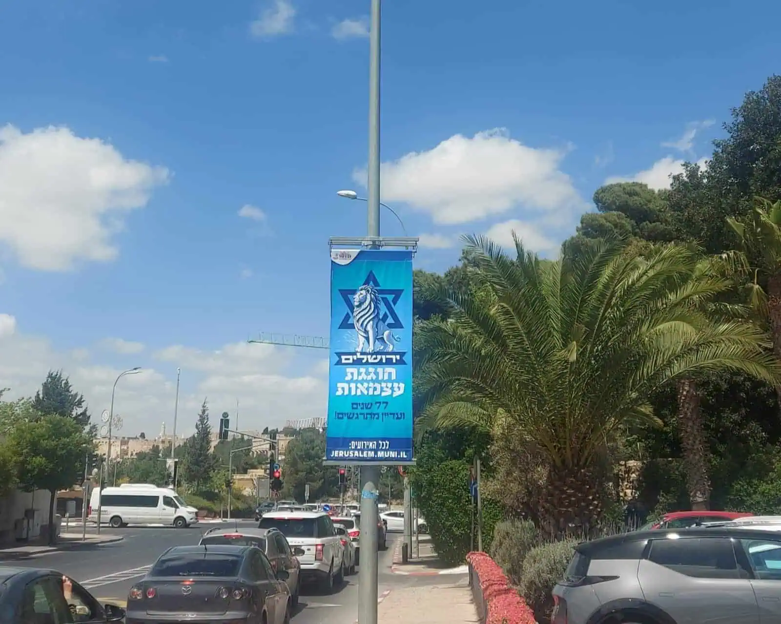 כרזת חגיגות יום העצמאות בירושלים, על רקע שמיים כחולים ועצי דקל