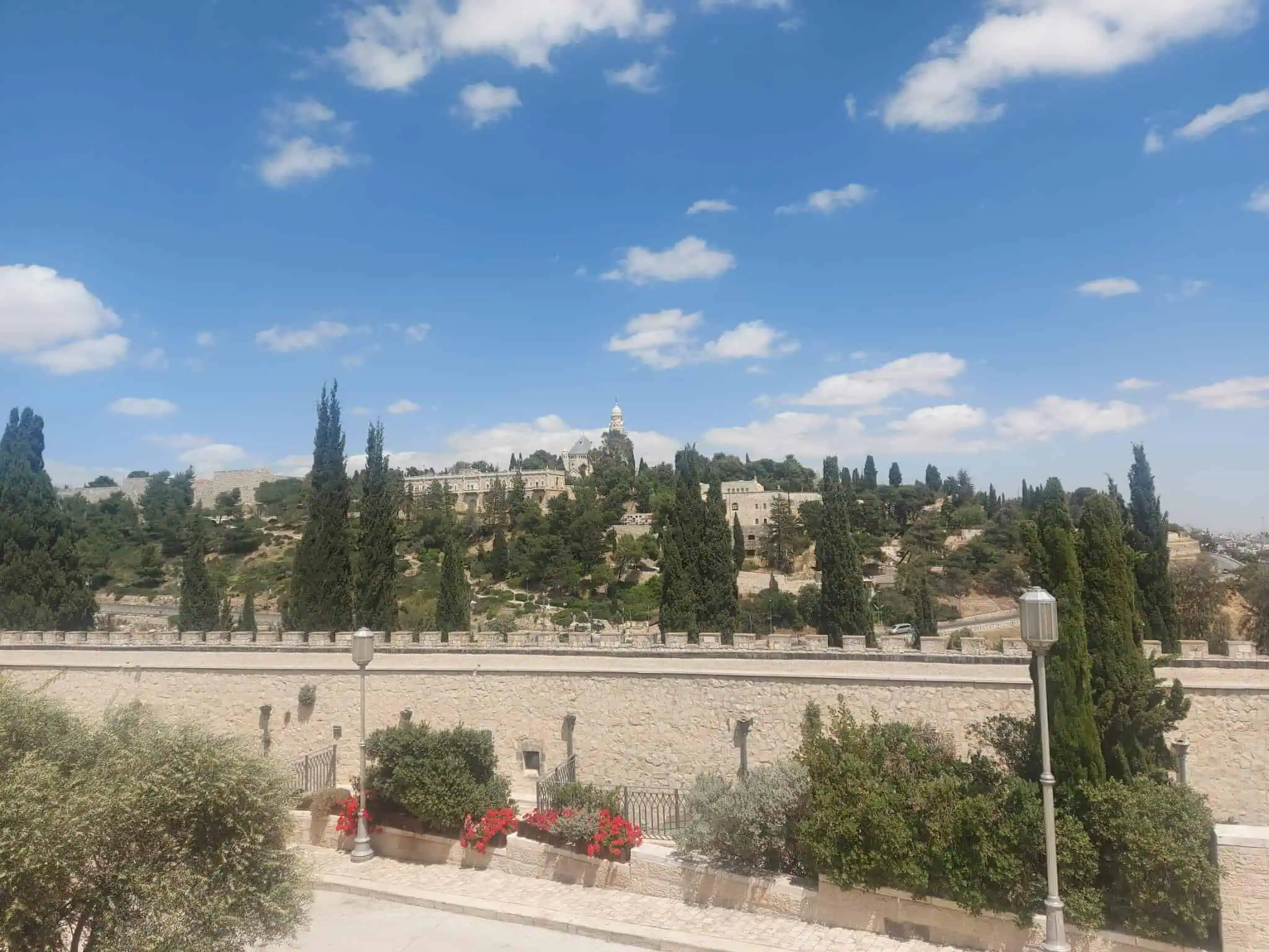 נוף פתוח לירושלים תחת שמיים כחולים: מבט אל הר ציון וחומות העיר העתיקה ביום אביבי.