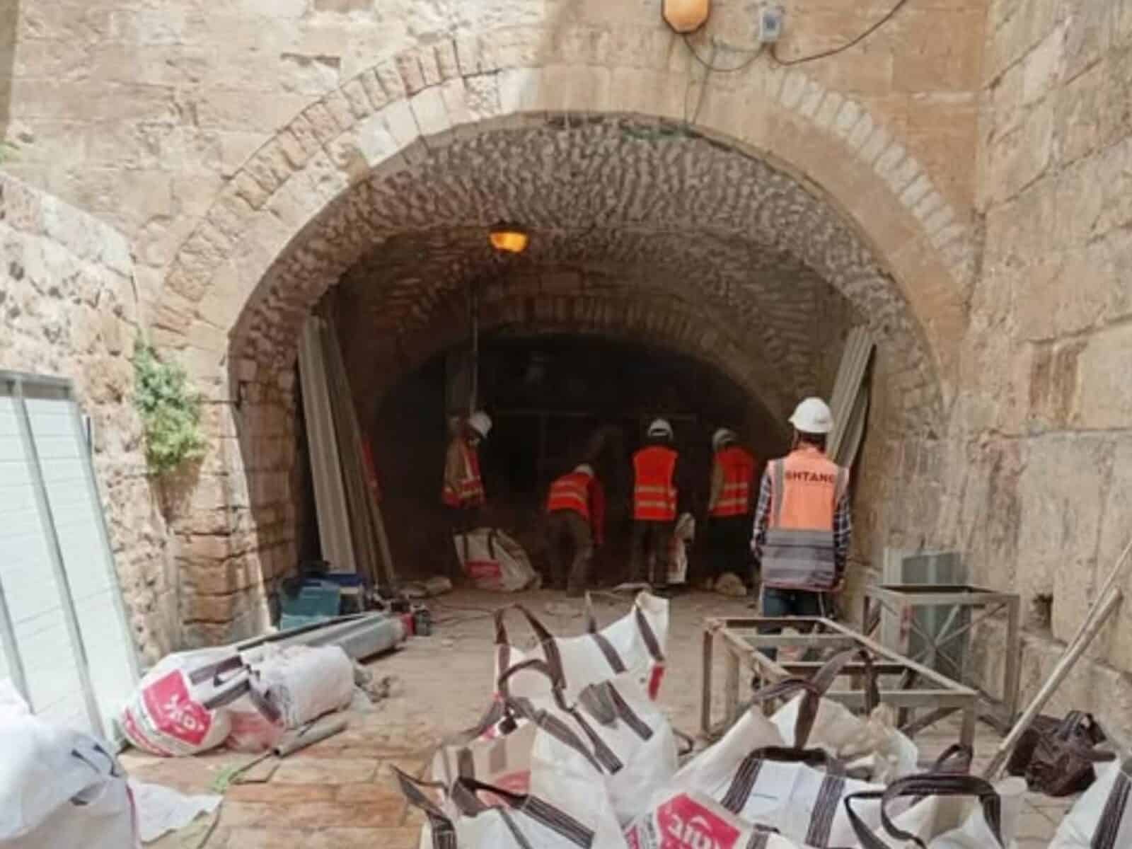 עבודות שיפוץ ותחזוקה בכותל הקטן בירושלים, פועלים ואנשי צוות בתוך קשת אבן עתיקה, הממחישה את נושא הכתבה