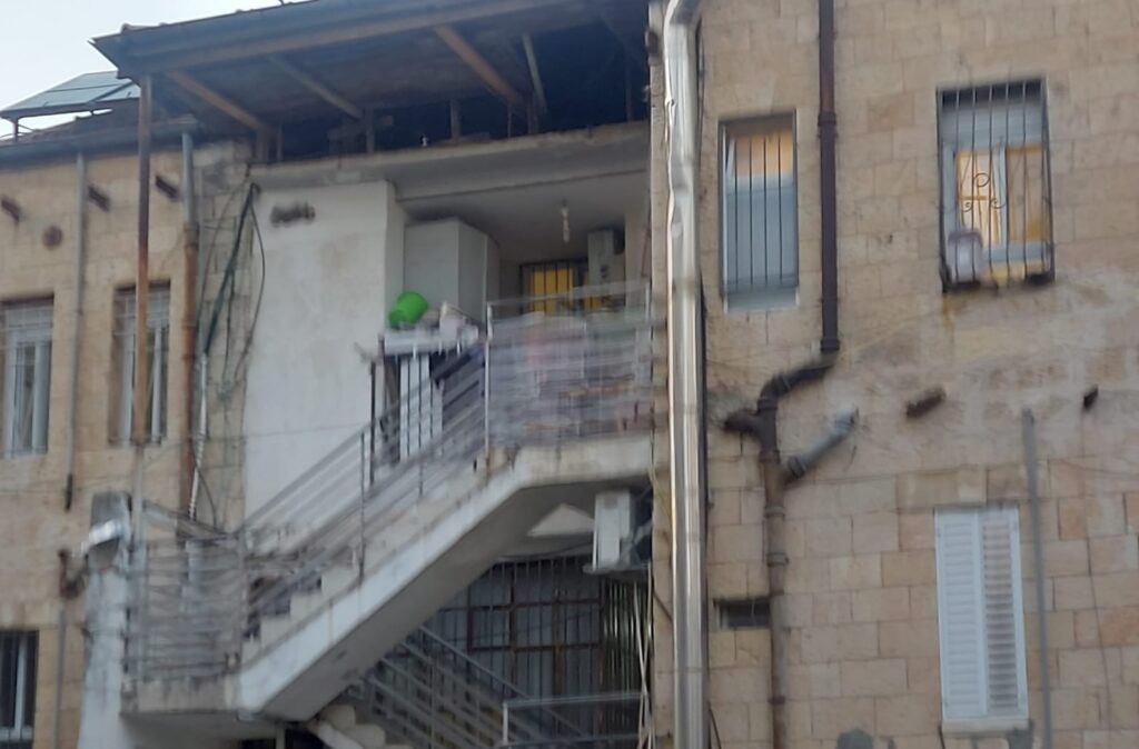חזית ירושלמית עם מרפסת אחורית עמוסה – כביסה, מקרר, ואילוצים שהופכים לפתרונות