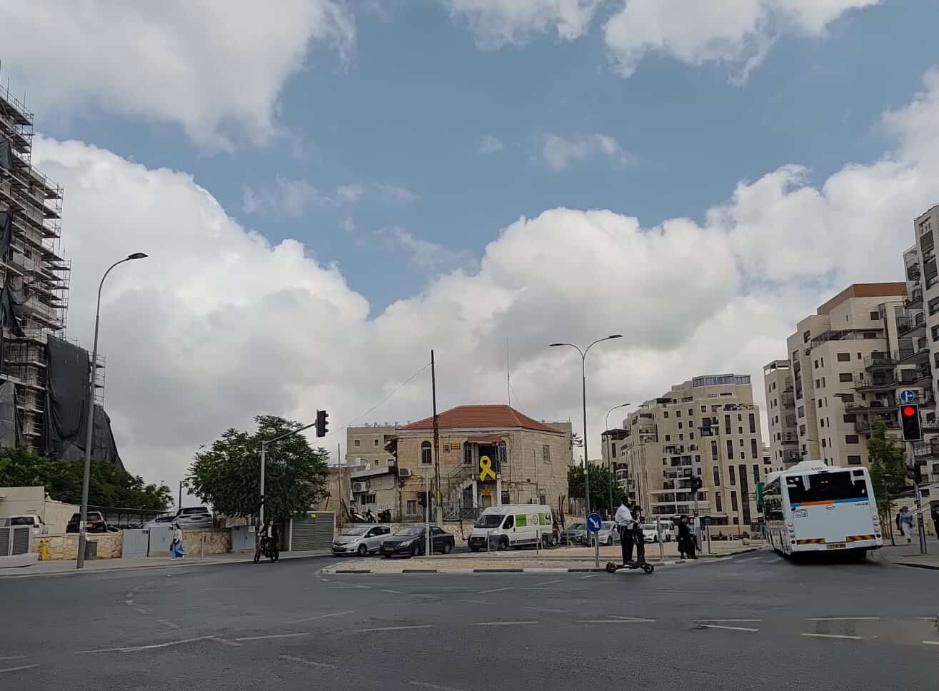רחוב בירושלים עם בניין הנושא סמל סרט צהוב, המשקף את הדופק והאווירה העירונית.