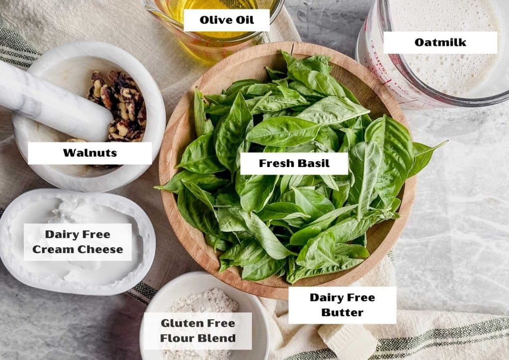 ingredients laying on counter top of fresh basil, dairy free cream cheese, walnuts and dairy free ingredients