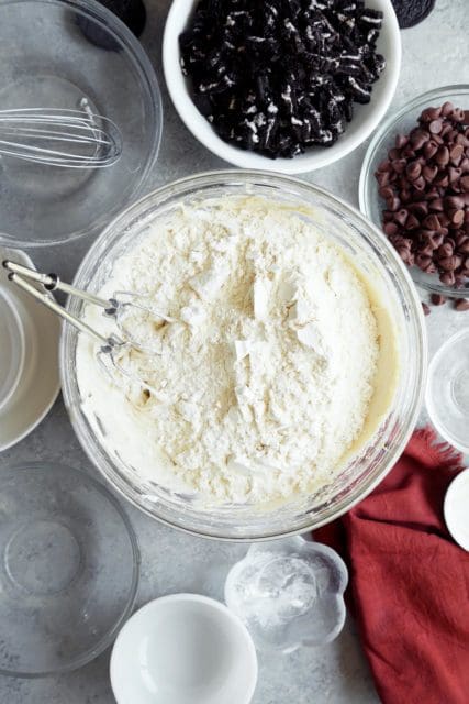 Dry ingredients added to a medium bowl of cookies and cream cookie batter.