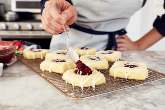 Spooning more cranberry sauce atop scones.