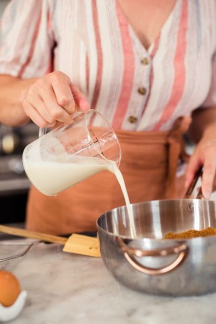 Adding coconut milk to gluten-freesweet potato pie filling.