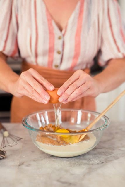 Cracking a brown egg into pie filling.