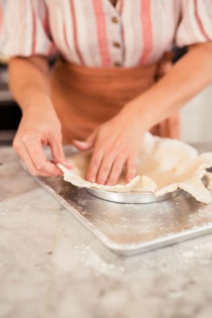 Placing pie crust in baking dish.