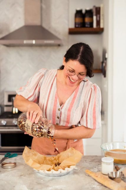 Joy the Baker pouring dried beans into parchment lined gluten free crust