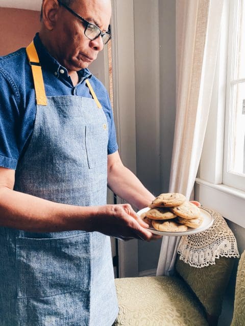 Dad holding a plate of browned butter chocolate chip cookies by the window.