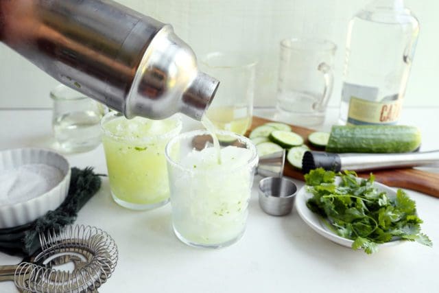 Silver shaker pouring margarita into glass.