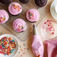 Piping bag and chocolate cupcakes on wire rack.