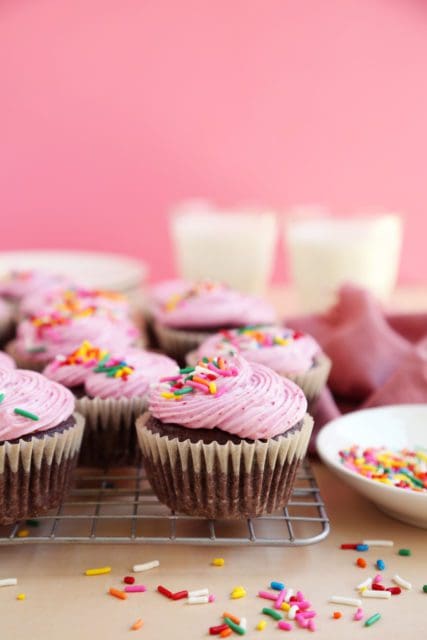 Glasses of milk and frosted small batch chocolate cupcakes on a wire rack