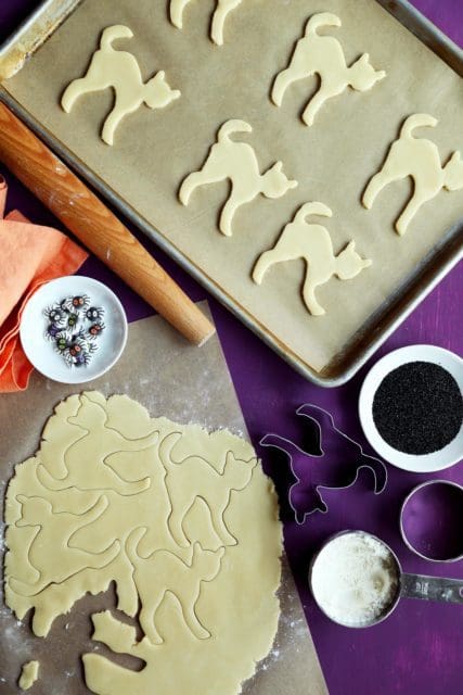 Sugar cookie dough rolled out and cut into scared cat shapes.