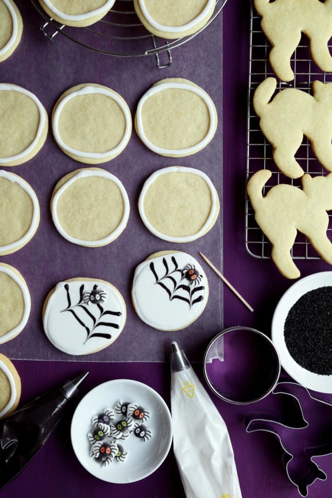 Frosting Halloween sugar cookies with white royal icing