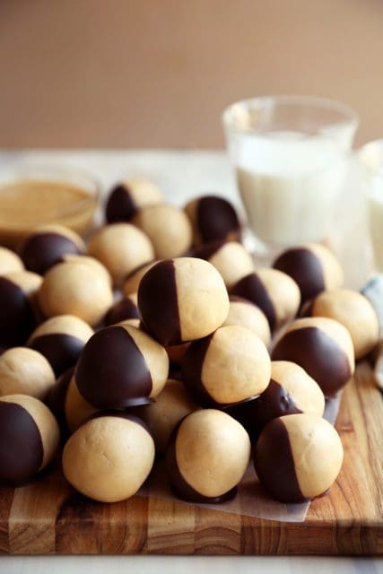 Peanut butter balls dipped in chocolate and piled on a board.