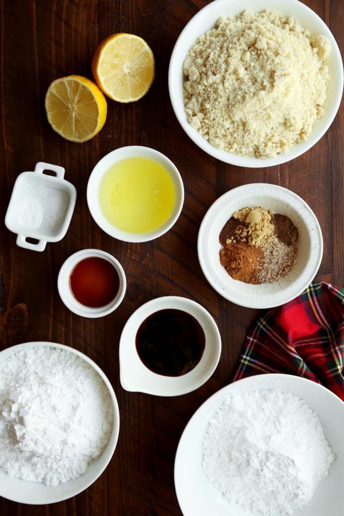 Ingredients for almond flour cookies in small bowls on a wooden surface.