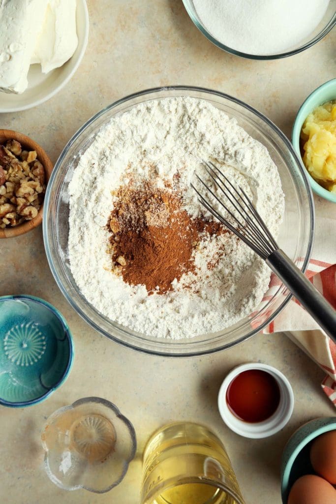 Dry ingredients for carrot cake in a medium bowl with whisk.