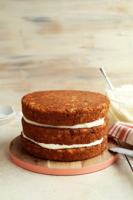 Frosting three layers of carrot cake.