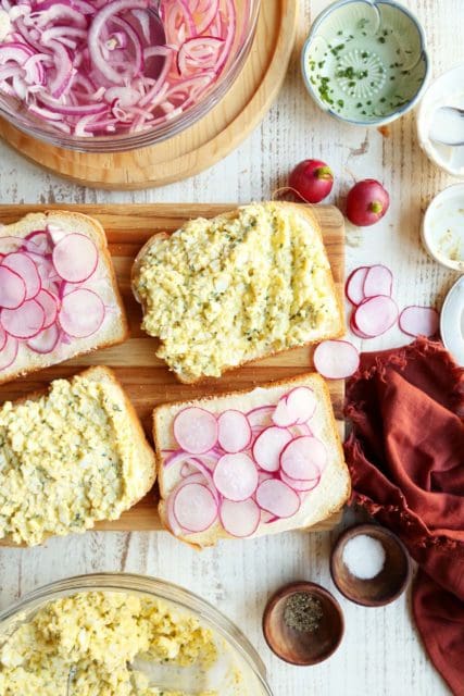 Making egg salad sandwiches.s Two pieces of bread with radishes and onions.
