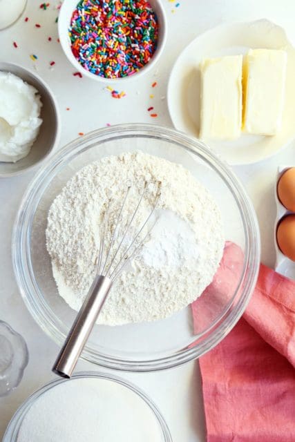 Dry ingredients for funfetti cake in a large bowl with whisk.