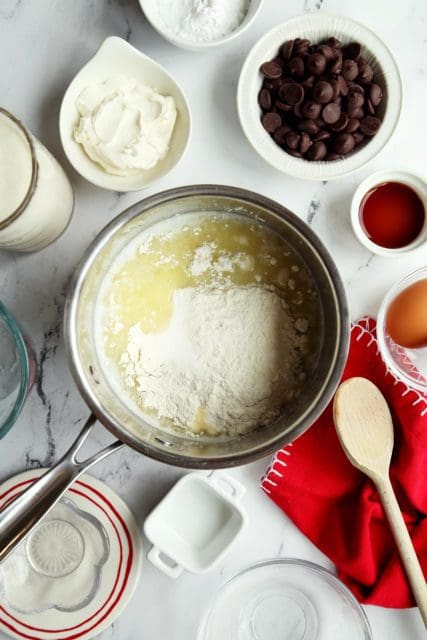 Flour added to eclair recipe batter in small pot.