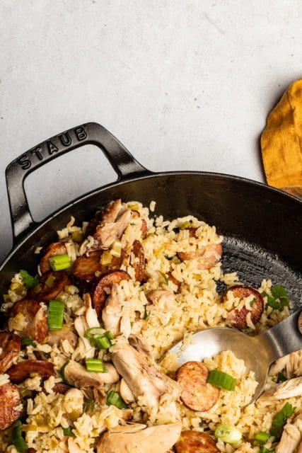 Sasuage and chicken jambalaya recipe with spoon in pot.