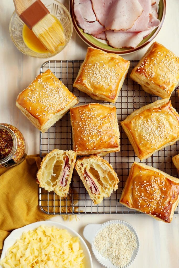 Baked ham and cheese croissants, sliced in half, on a wire rack.