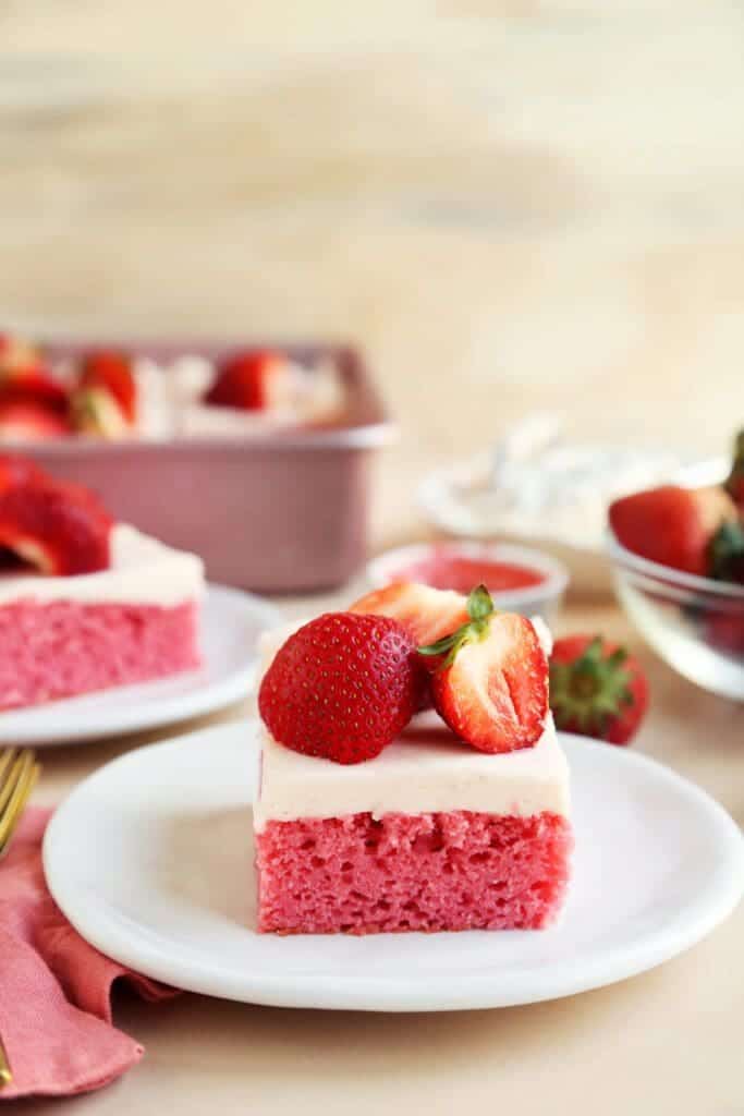 strawberry sheet cake on a plate with strawberries on top.