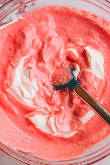 Stirring Cool Whip into cranberry pie filling.