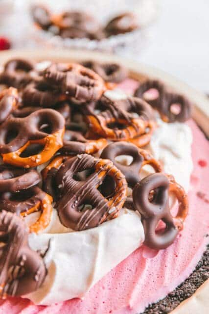Cranberry pie topped with whipped cream and chocolate covered pretzels.