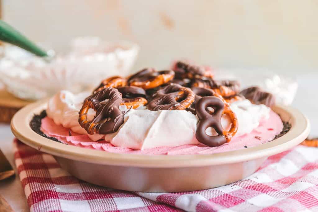 Cranberry pie topped with whipped cream and chocolate covered pretzels.