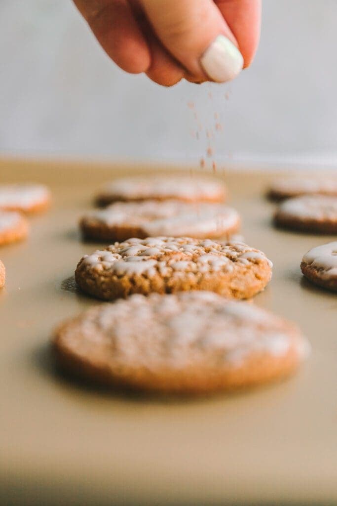 Sprinkling nutmeg on iced cookies