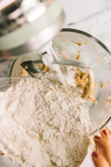 mixing dry ingredients into white chocolate macadamia nut cookie batter to combine