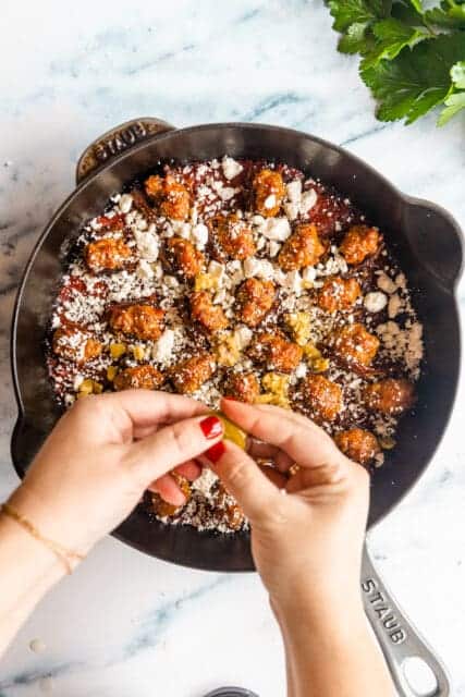 crumbling herbs and cheese over stuffed dates