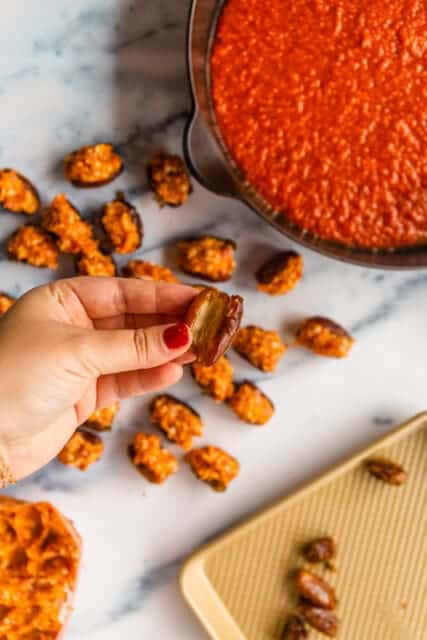 preparing dates to be stuffed with sausage and set in tomato sauce