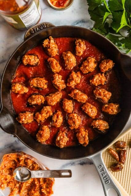 stuffed dated sitting in tomato sauce in a cast iron pan