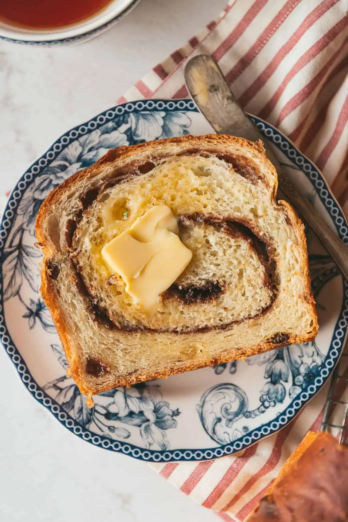 a lovely pat of butter melting on top of a slice of cinnamon raisin swirl bread